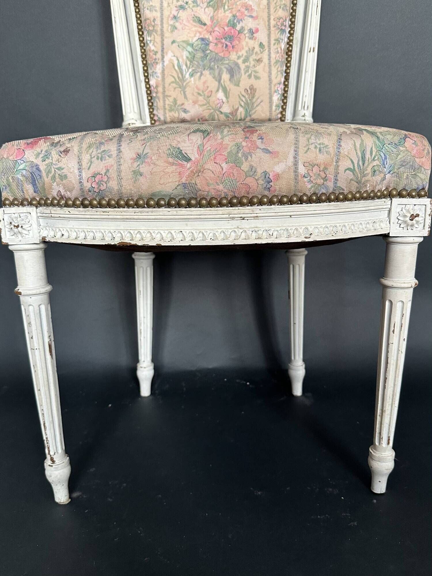 Antique Louis XVI style chair with patinated wood and floral fabric.