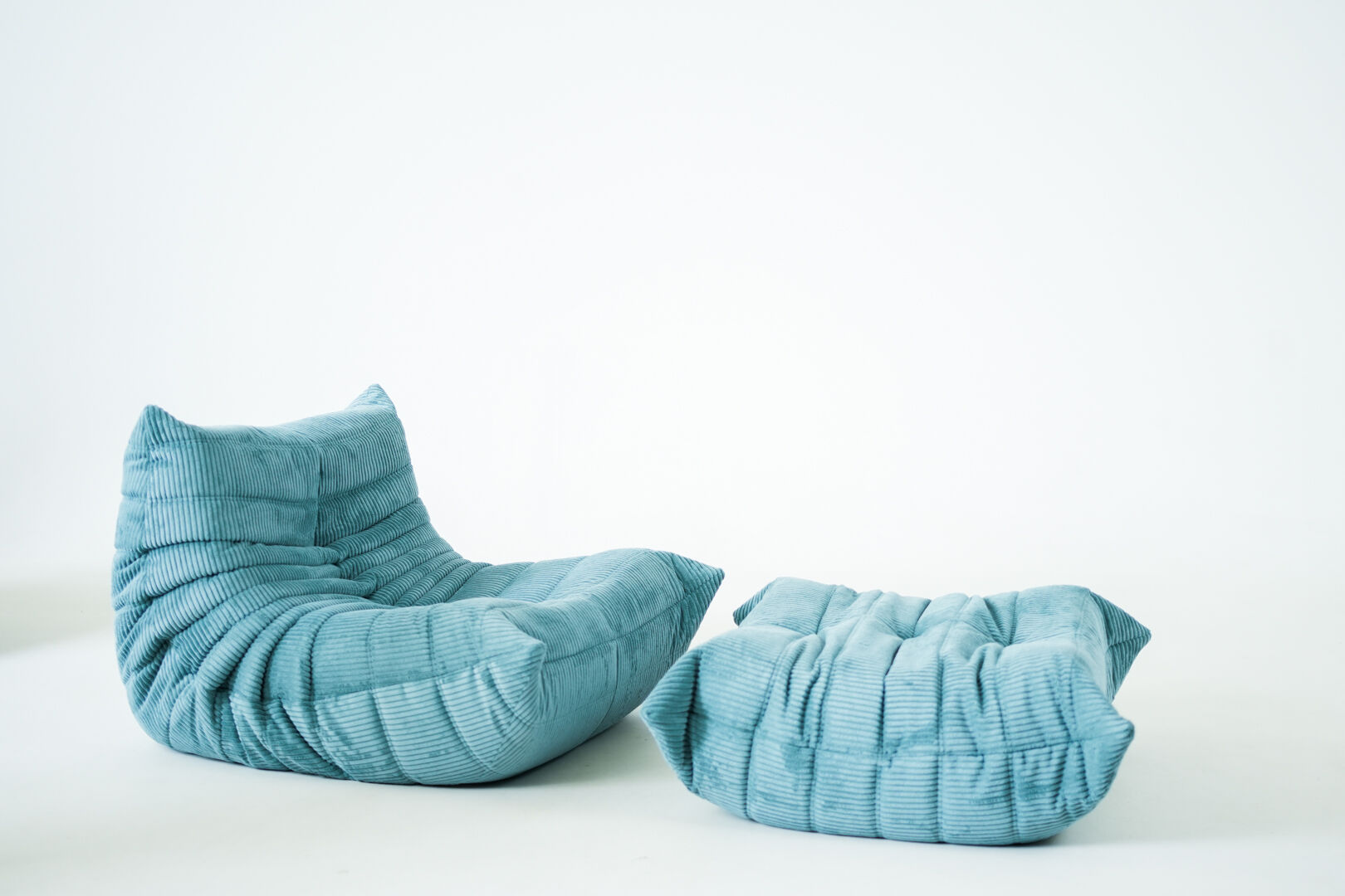 Ensemble de fauteuil et pouf Togo en velours côtelé bleu clair.