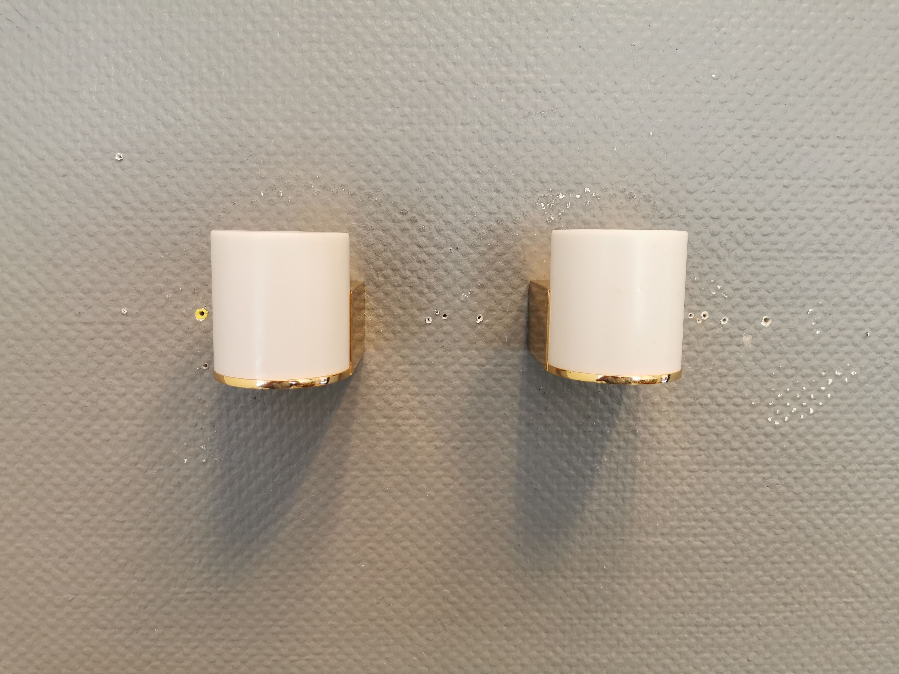 Wall lamps with milky white acrylic plastic shades and solid brass bases