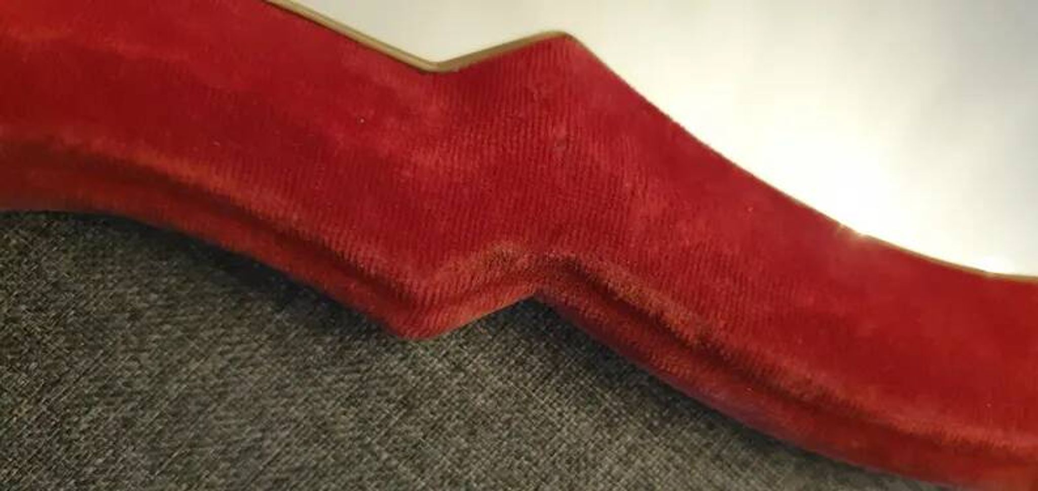 Vintage mirror with a scalloped shape in burgundy velvet and a golden trim.