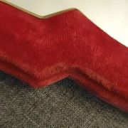 Vintage mirror with a scalloped shape in burgundy velvet and a golden trim.