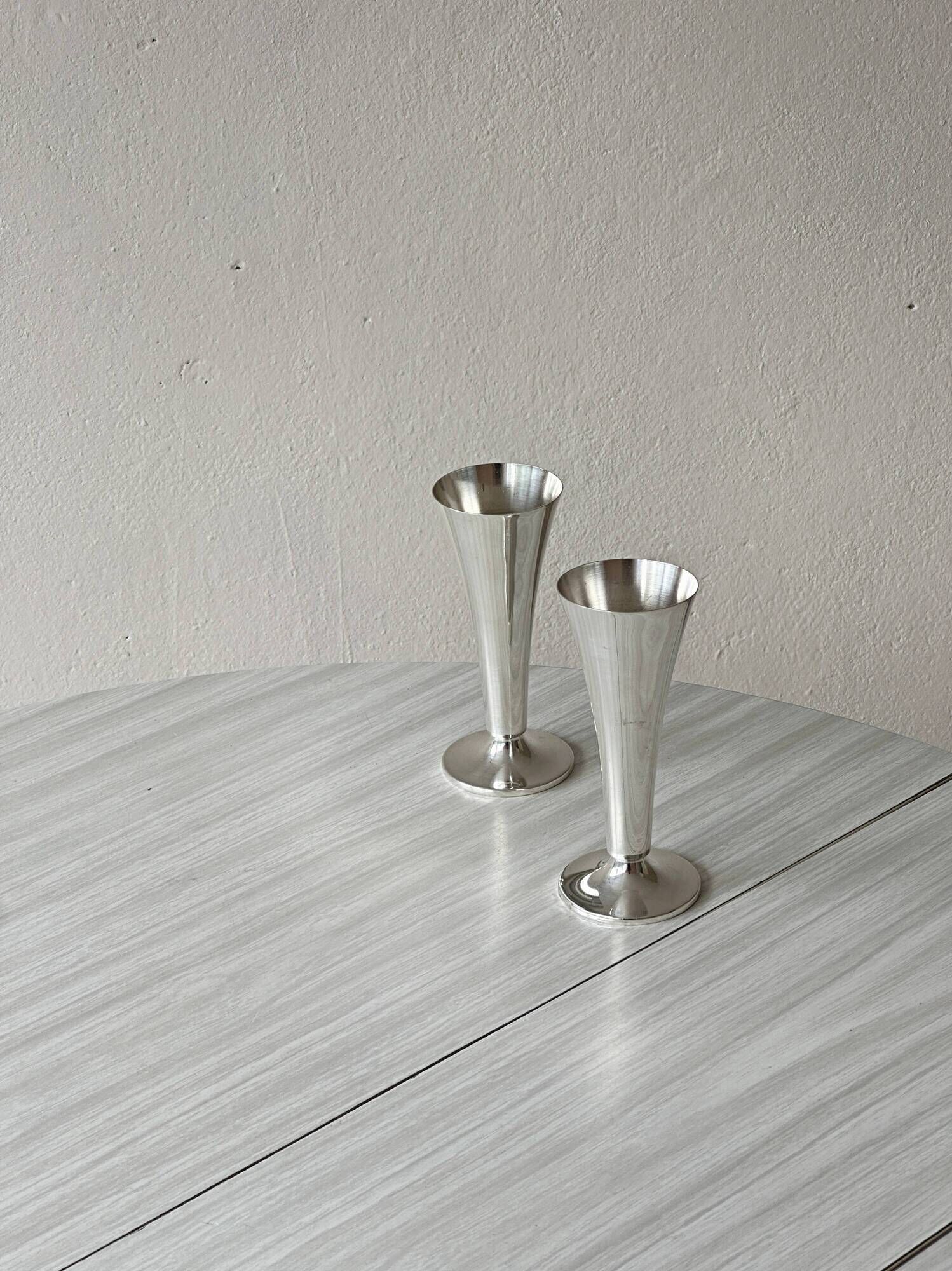 Two silver-coloured lightweight metal flower vases.