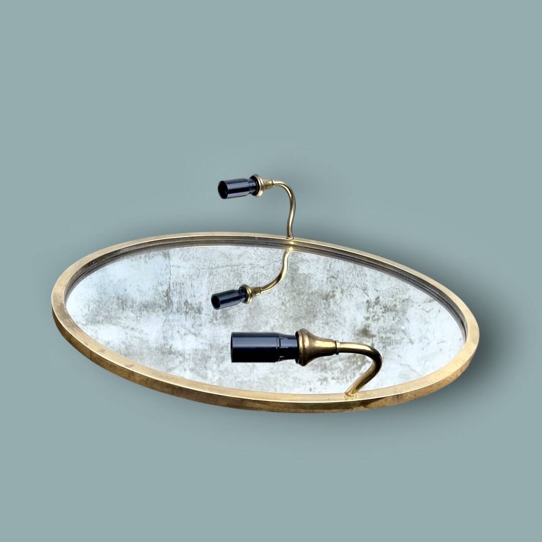 Oval wall mirror in gilded brass with double sconces – 1950s/60s