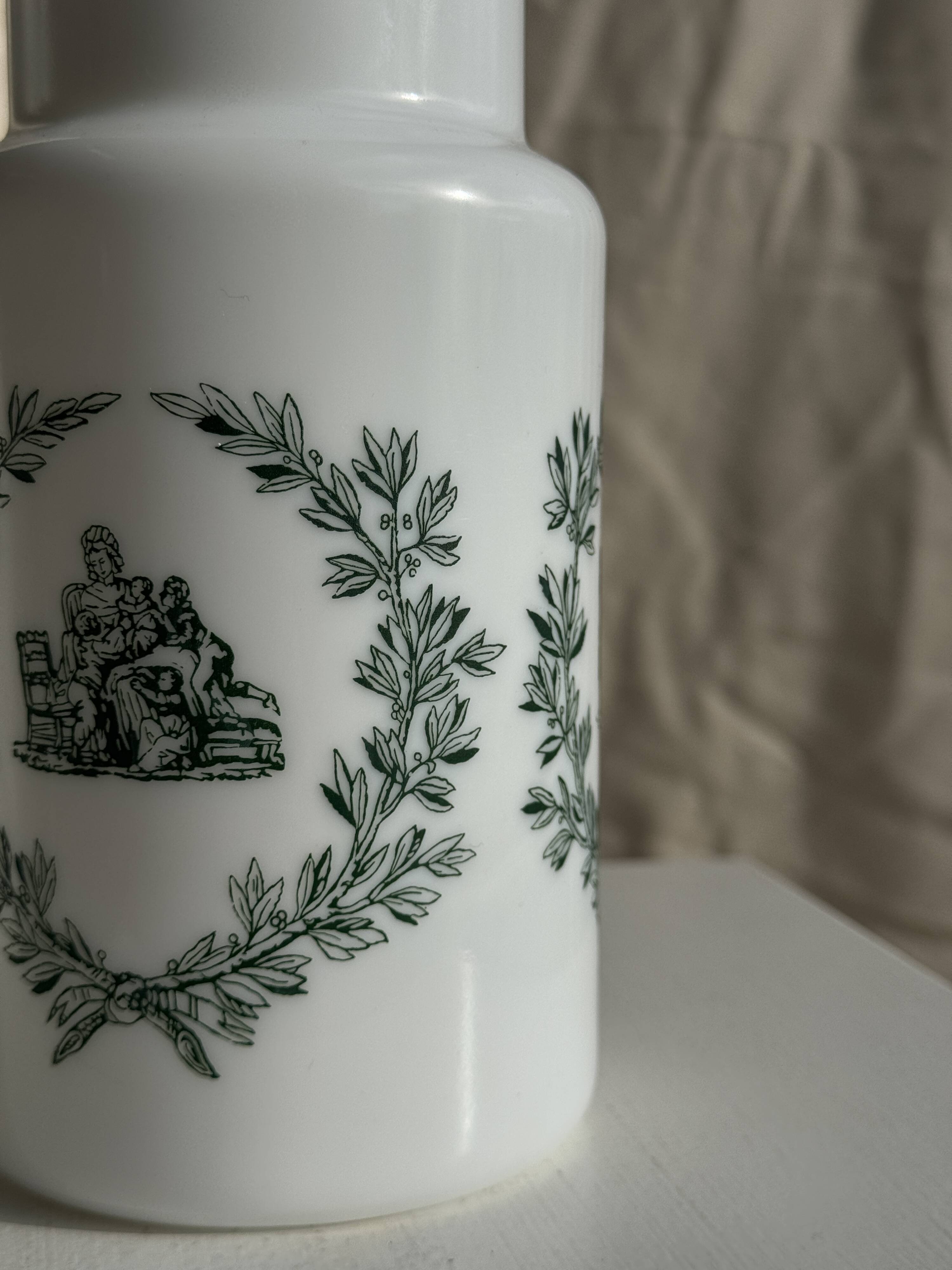 A pair of white glass bottles with Italian green patterns.