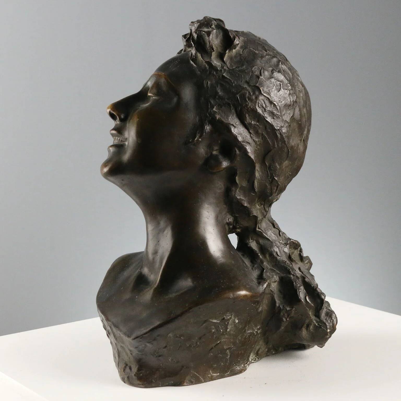 Ancient sculpture of a young woman's face in bronze, 19th-20th century.