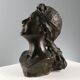Ancient sculpture of a young woman's face in bronze, 19th-20th century.