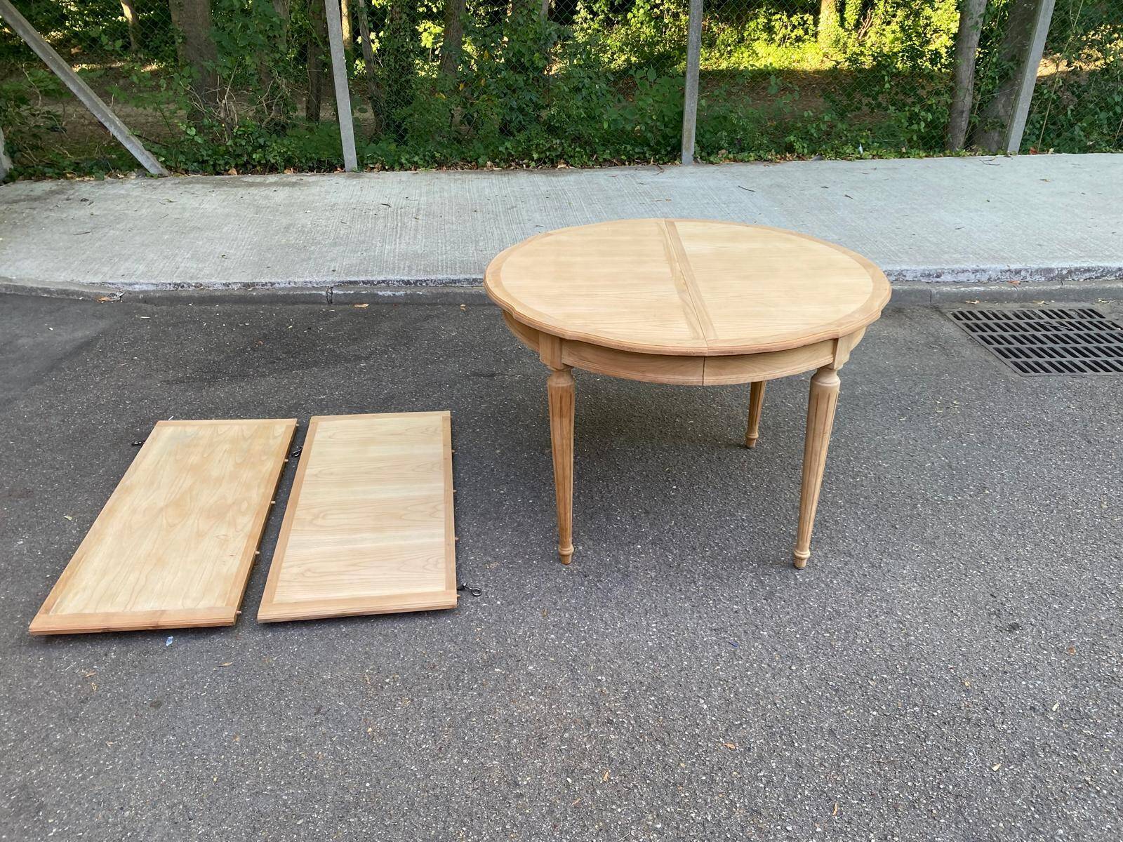 Extendable round table in renovated Louis XVI style, made of light wood, with 2 extensions.