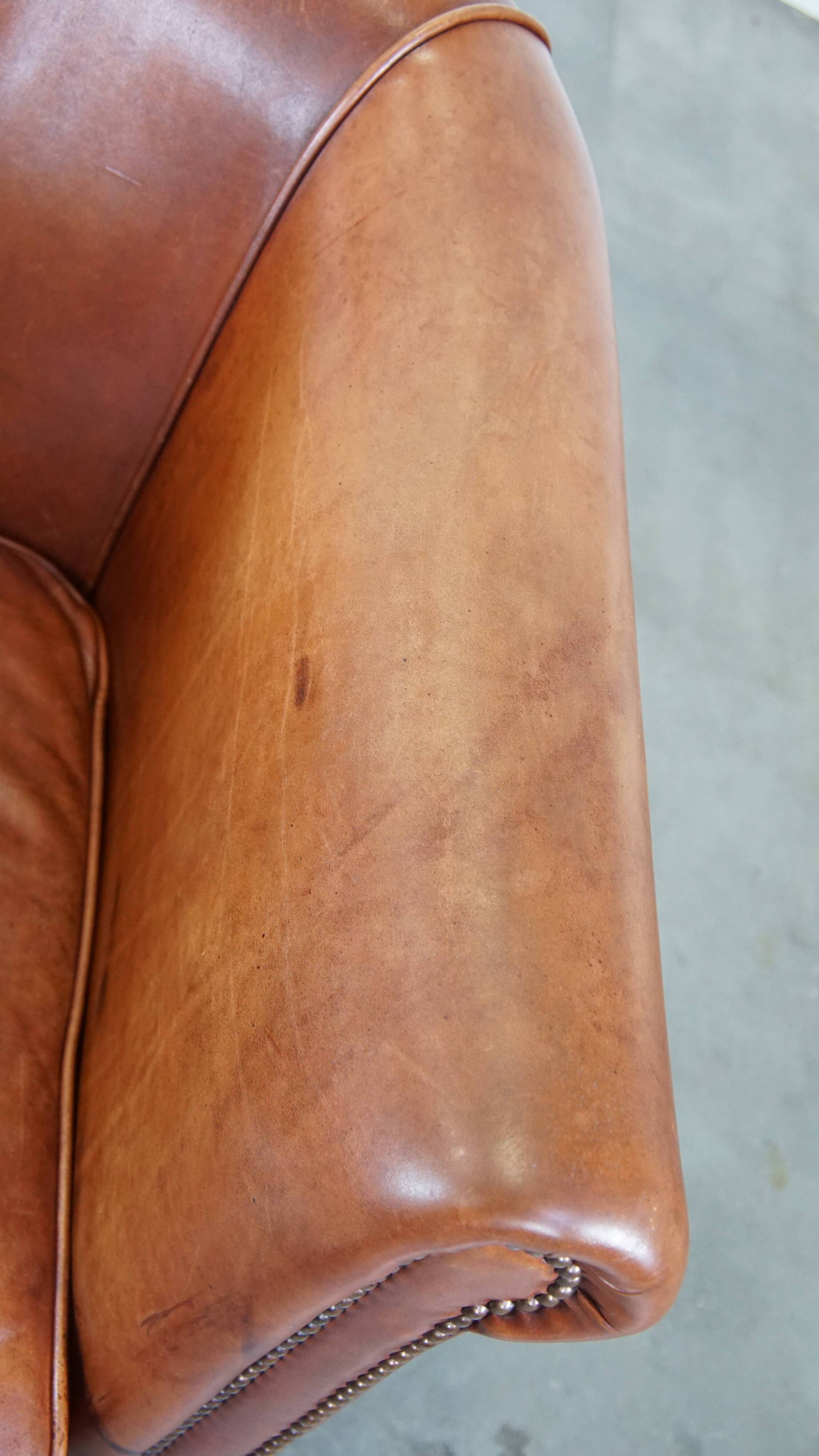Cognac-colored cow leather club chair finished with decorative nails in English style