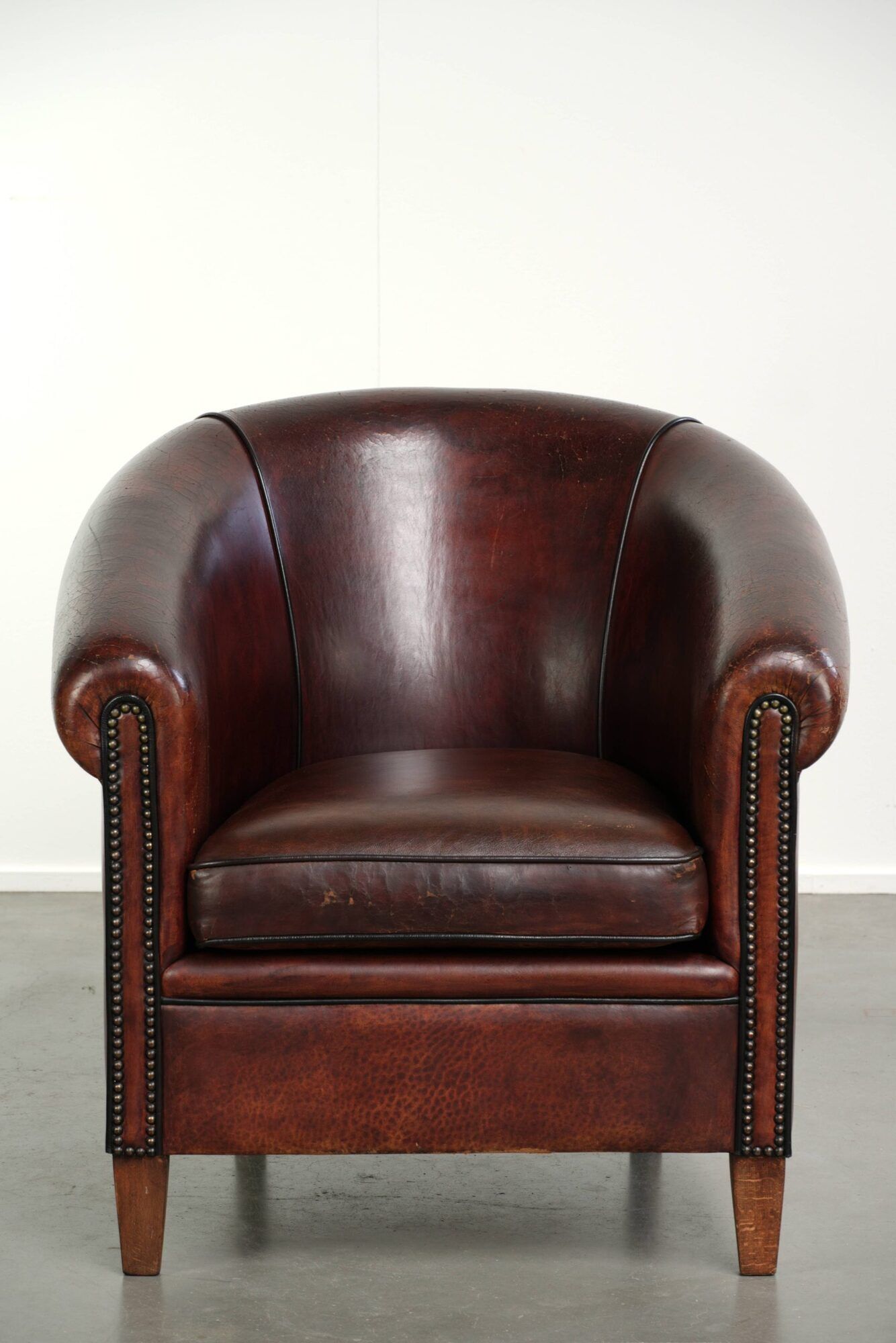 Vintage sheepskin club armchair with decorative nails and black piping