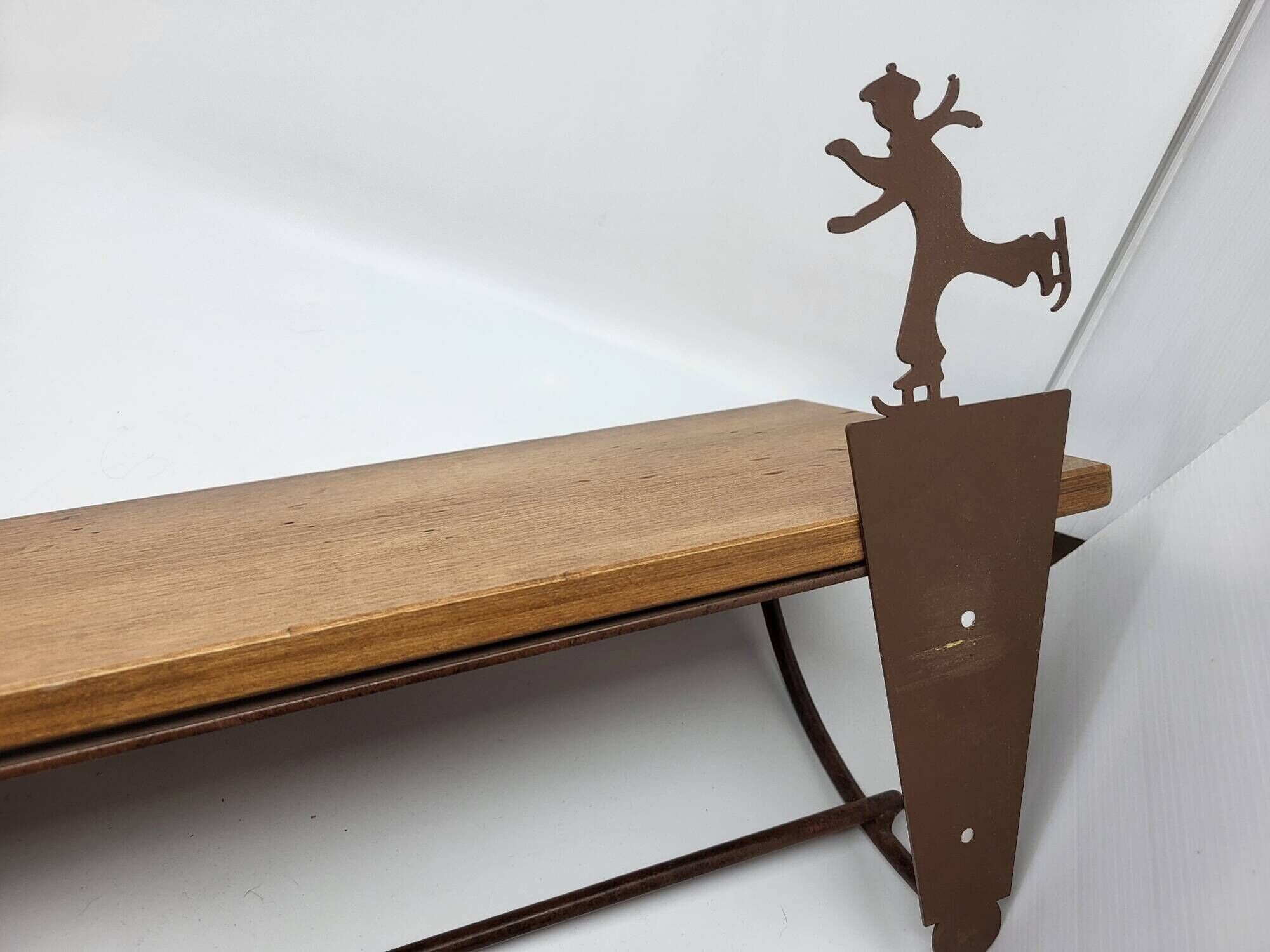 Wall shelf in wood and metal with a decoration of ice skaters.