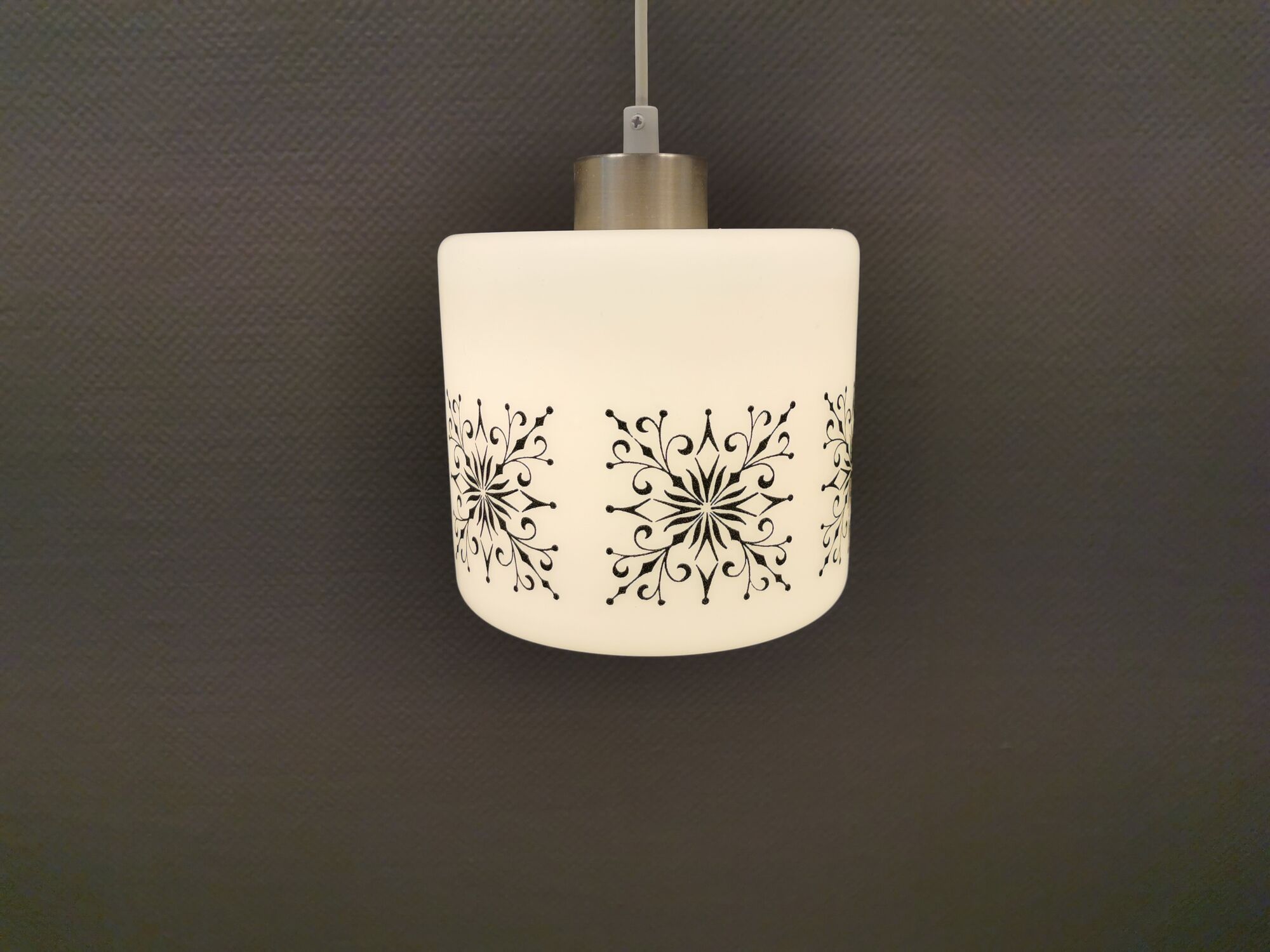 Scandinavian hanging lamp in white glass with inlayed black motifs.