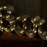 Enseigne lumineuse en lettrage aluminium formant le mot "bar"