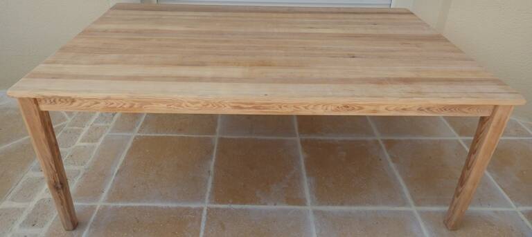 Large natural wood table with rectangular top supported by legs
