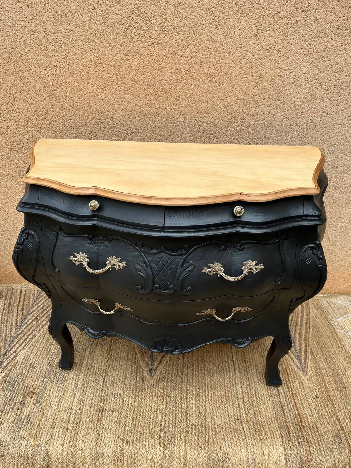 Curved commode painted in black and wood.