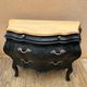 Curved commode painted in black and wood.