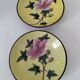 A pair of vintage Chinese decorative plates with floral designs on a yellow background.
