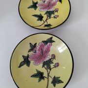 A pair of vintage Chinese decorative plates with floral designs on a yellow background.