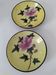 A pair of vintage Chinese decorative plates with floral designs on a yellow background.