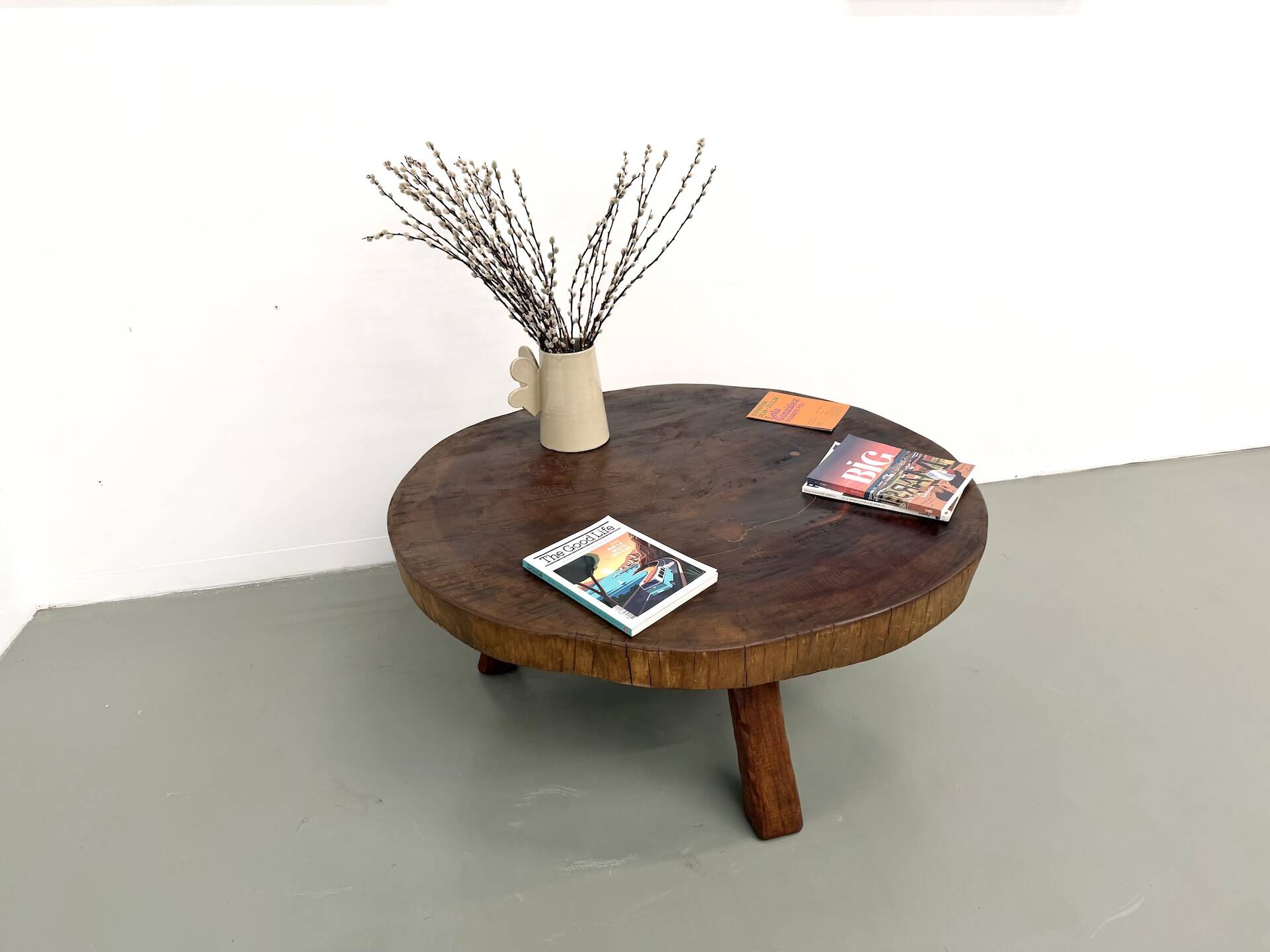 Brutalist coffee table in solid teak, monolithic slab, tripod base.