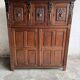 Armoire ancienne en bois foncé sculpté, ornée de motifs floraux sculptés à la main et de poignées en métal.