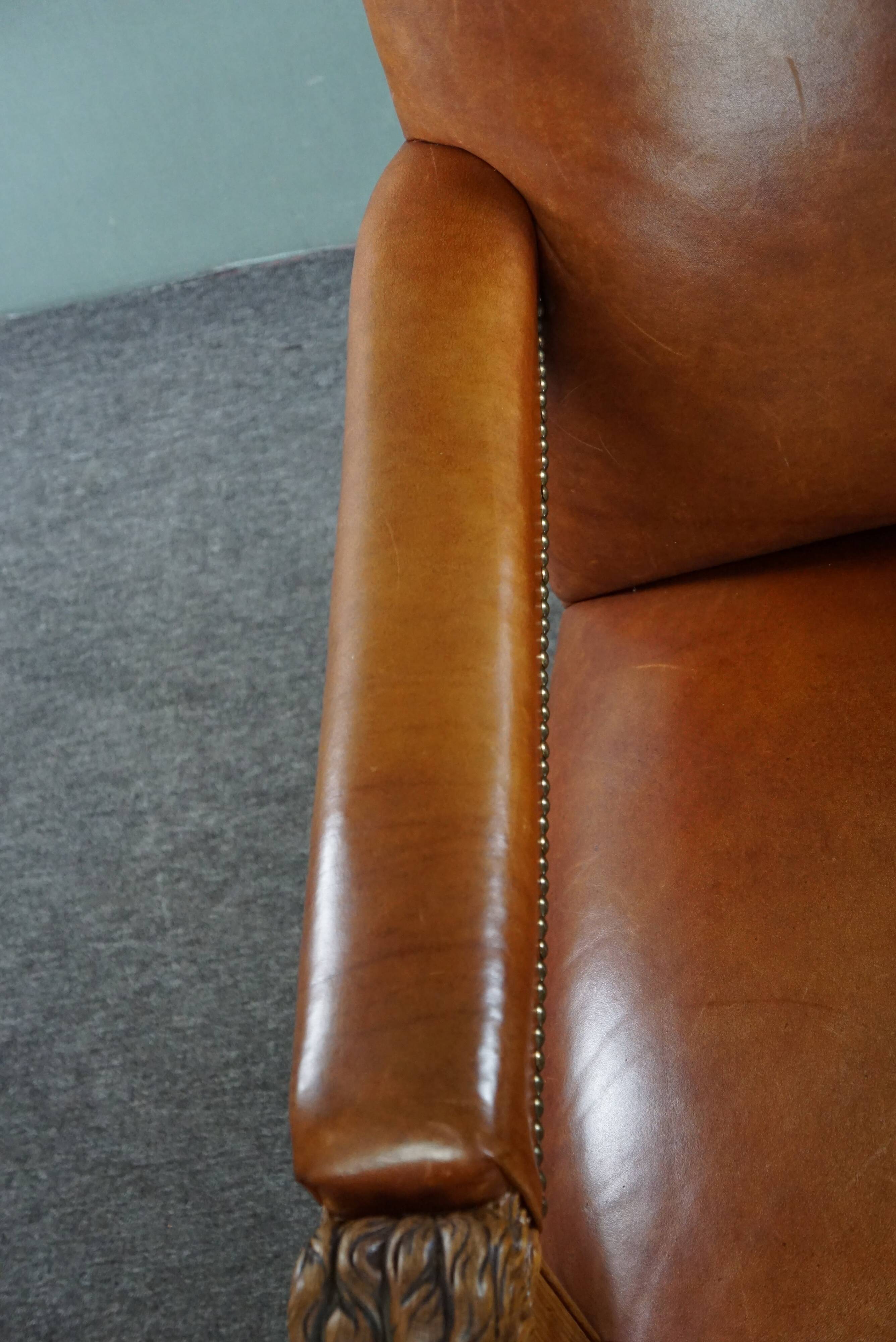 Armchair with lion heads reupholstered in cognac-colored cowhide leather