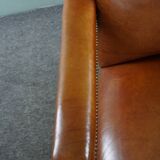 Armchair with lion heads reupholstered in cognac-colored cowhide