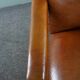 Armchair with lion heads reupholstered in cognac-colored cowhide leather