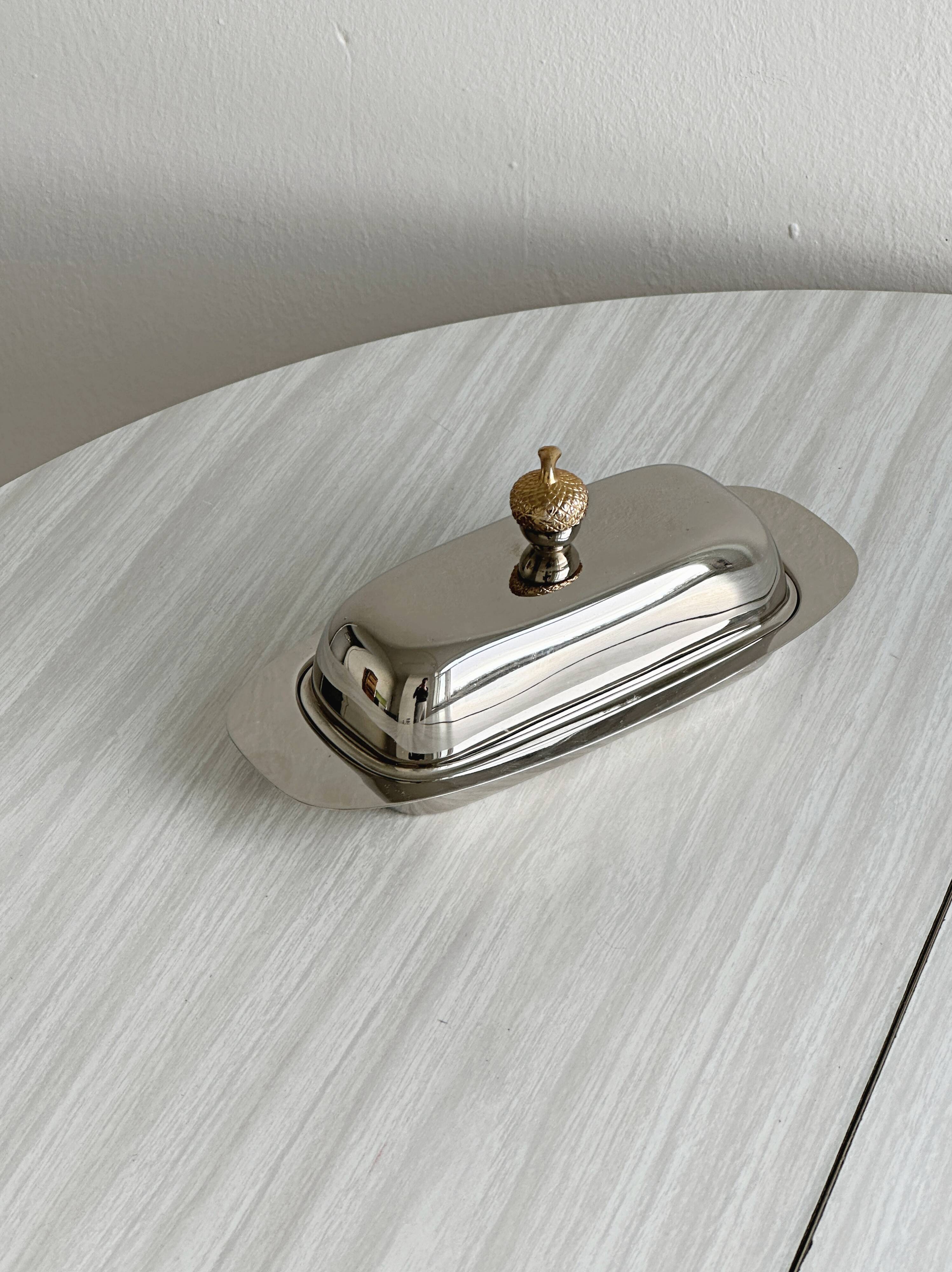 stainless steel butter dish with a golden knob