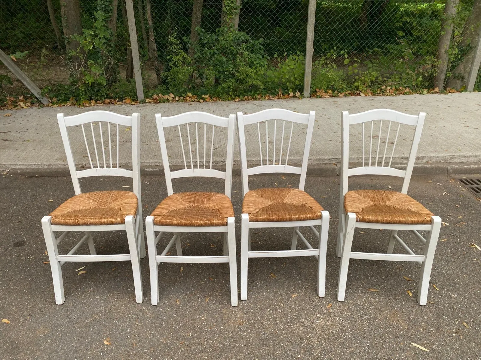 Set of 4 rustic white wooden chairs with straw seats.