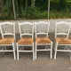 Set of 4 rustic white wooden chairs with straw seats.