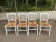 Set of 4 rustic white wooden chairs with straw seats.