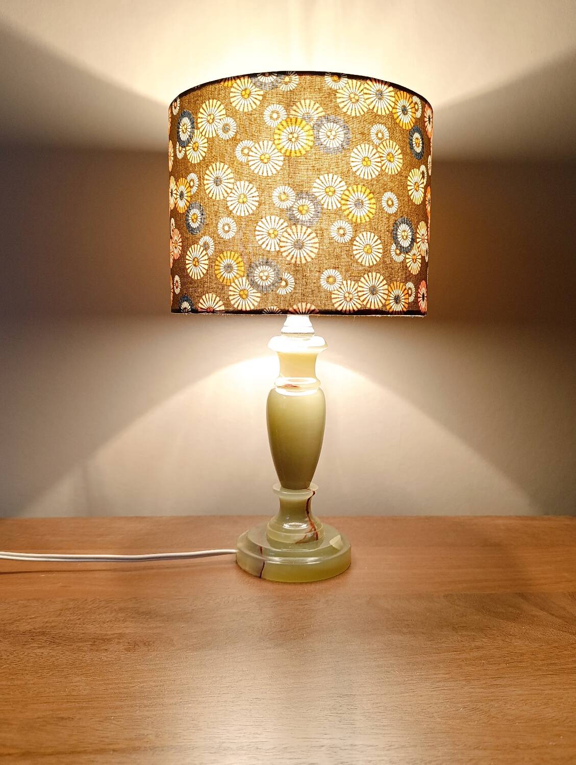 Table lamp with light green onyx base, fabric shade with a khaki background.