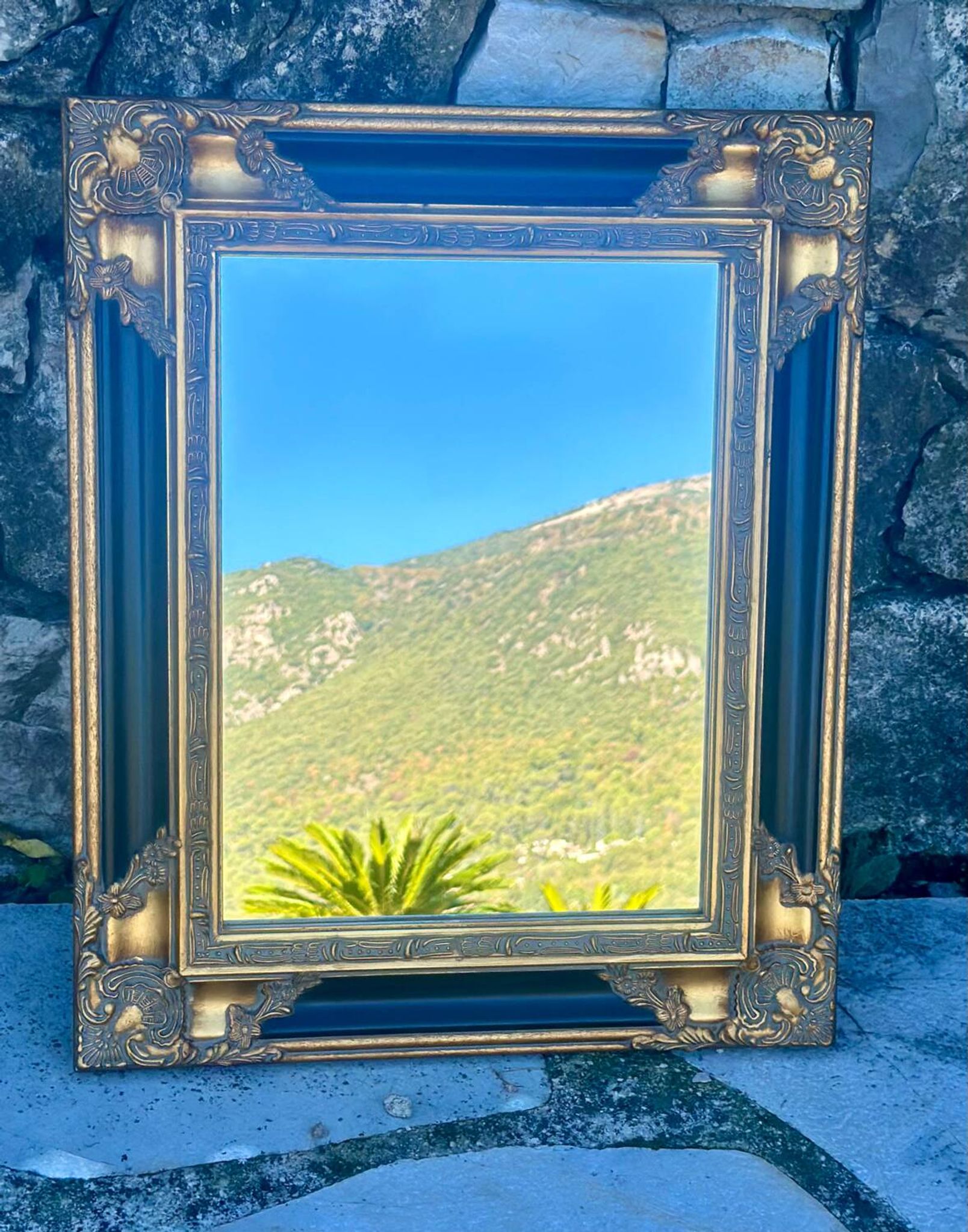 Miroir Baroque en bois doré sur fond noir.