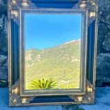 Baroque mirror in gilded wood on a black background.