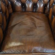 A well-maintained cowhide leather English Chesterfield armchair