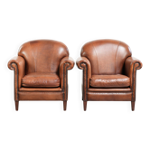 Ensemble de deux fauteuils en peau de mouton vintage ornés de clous décoratifs.