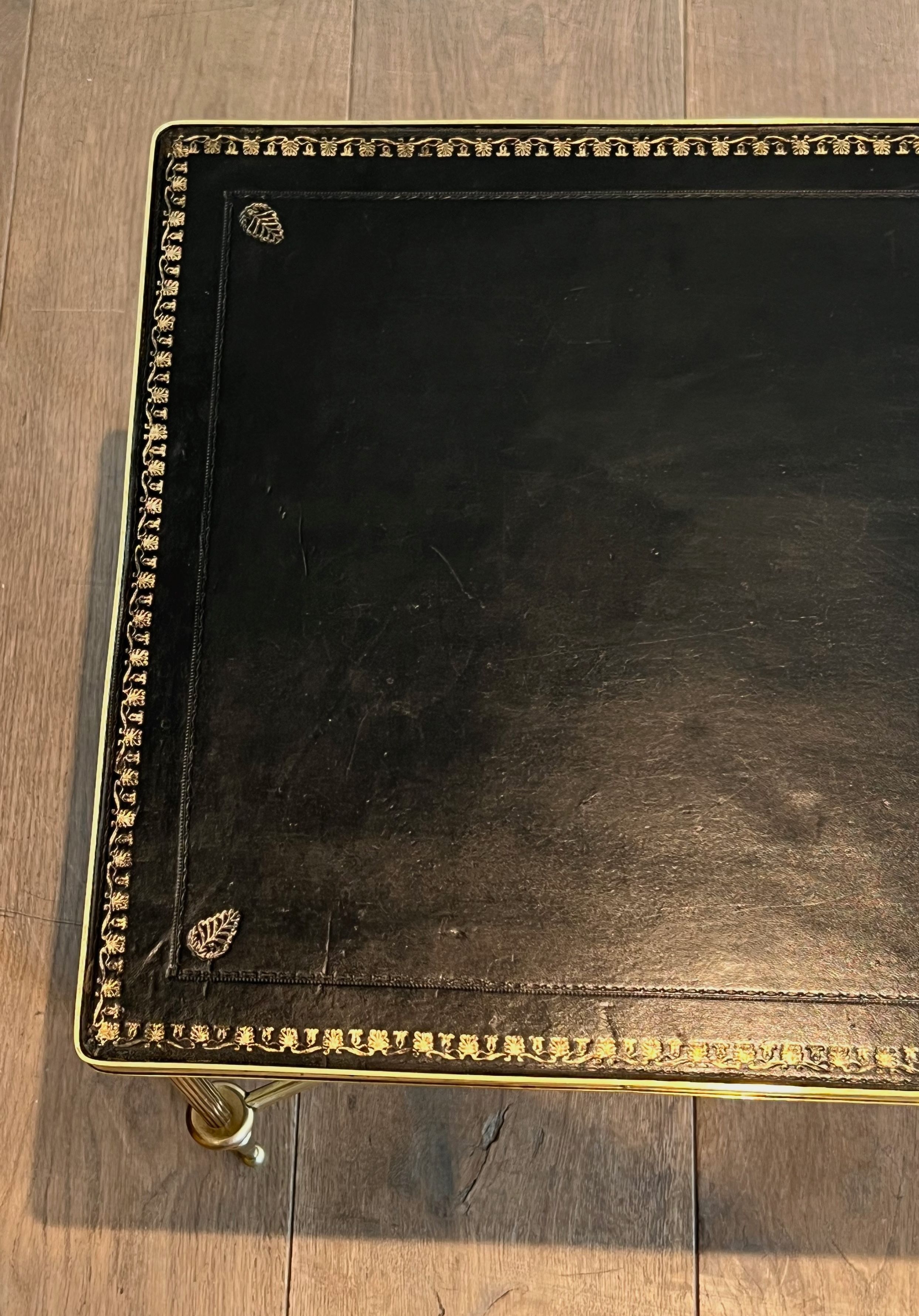 Neoclassical brass coffee table with a black leather top and golden borders from Maison Jansen.