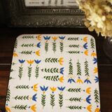 Vintage laminated wooden trivet with yellow, green, and blue flowers