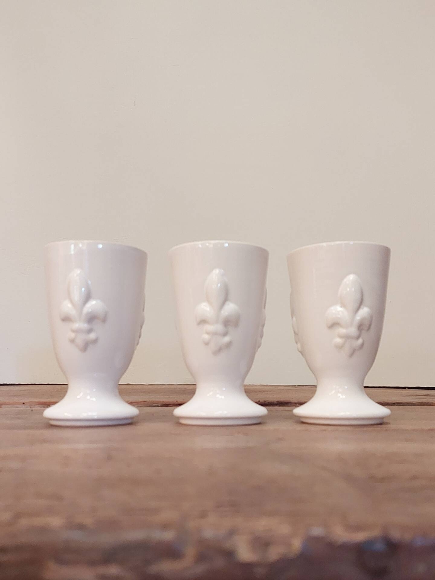 Three antique cups decorated with fleur-de-lis.