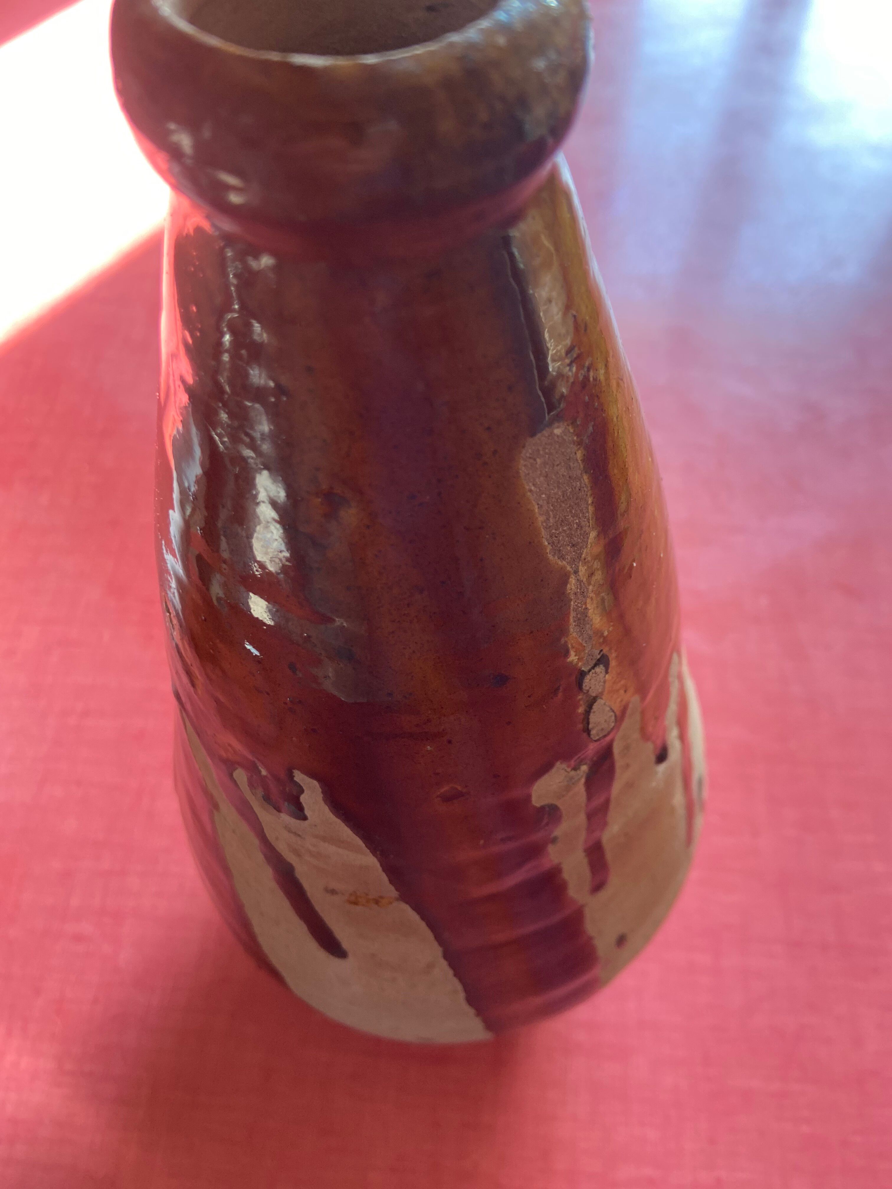 Large antique pottery bottle in glazed terracotta with drips.