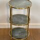 Round bronze side table with triple shelves of églomisé mirrors from Maison Baguès