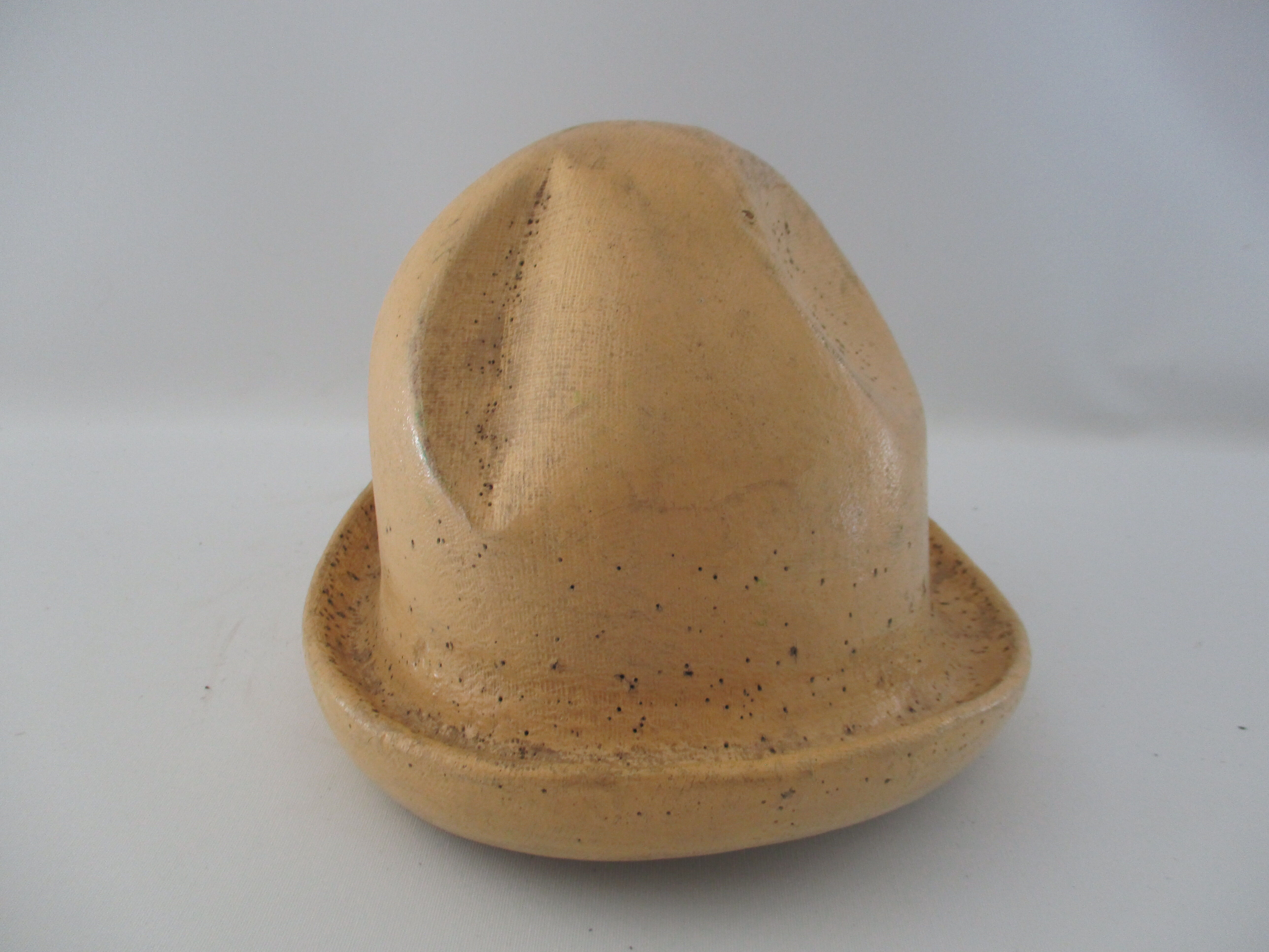 Shape of pressed plaster hat with surface and textile fiber of yellowish color,