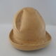 Shape of pressed plaster hat with surface and textile fiber of yellowish color,