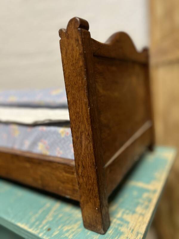 Old doll's bed in varnished wood