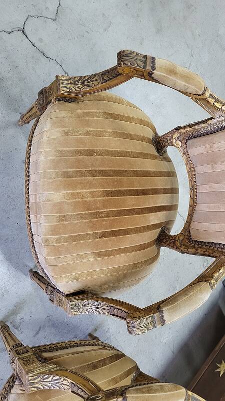 A pair of gilded wooden armchairs in the Louis XVI style.