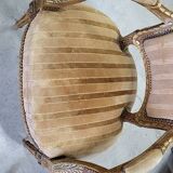 A pair of gilded wooden armchairs in the Louis XVI style.