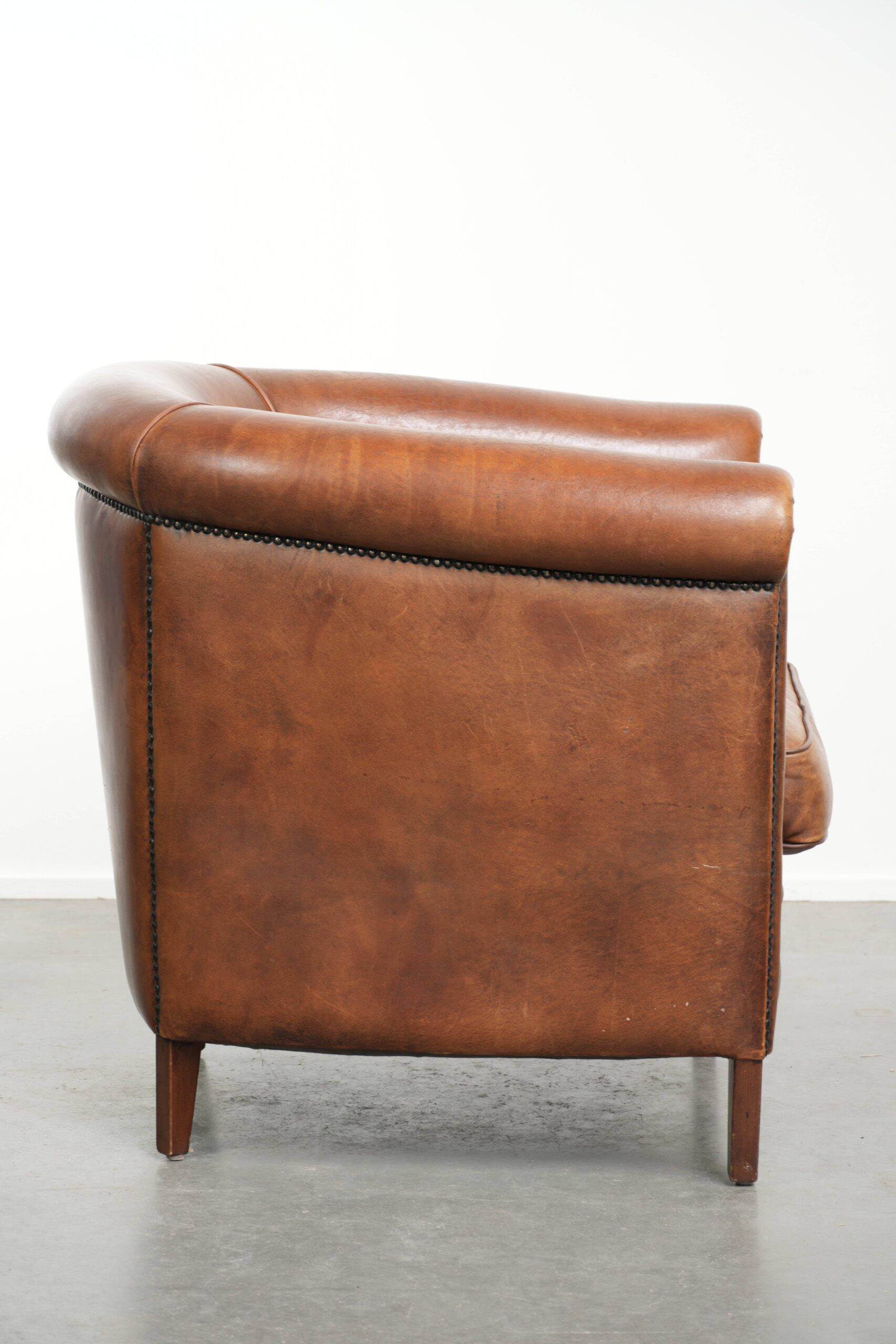 Sheepskin club armchair with a cognac colour finished with decorative nails