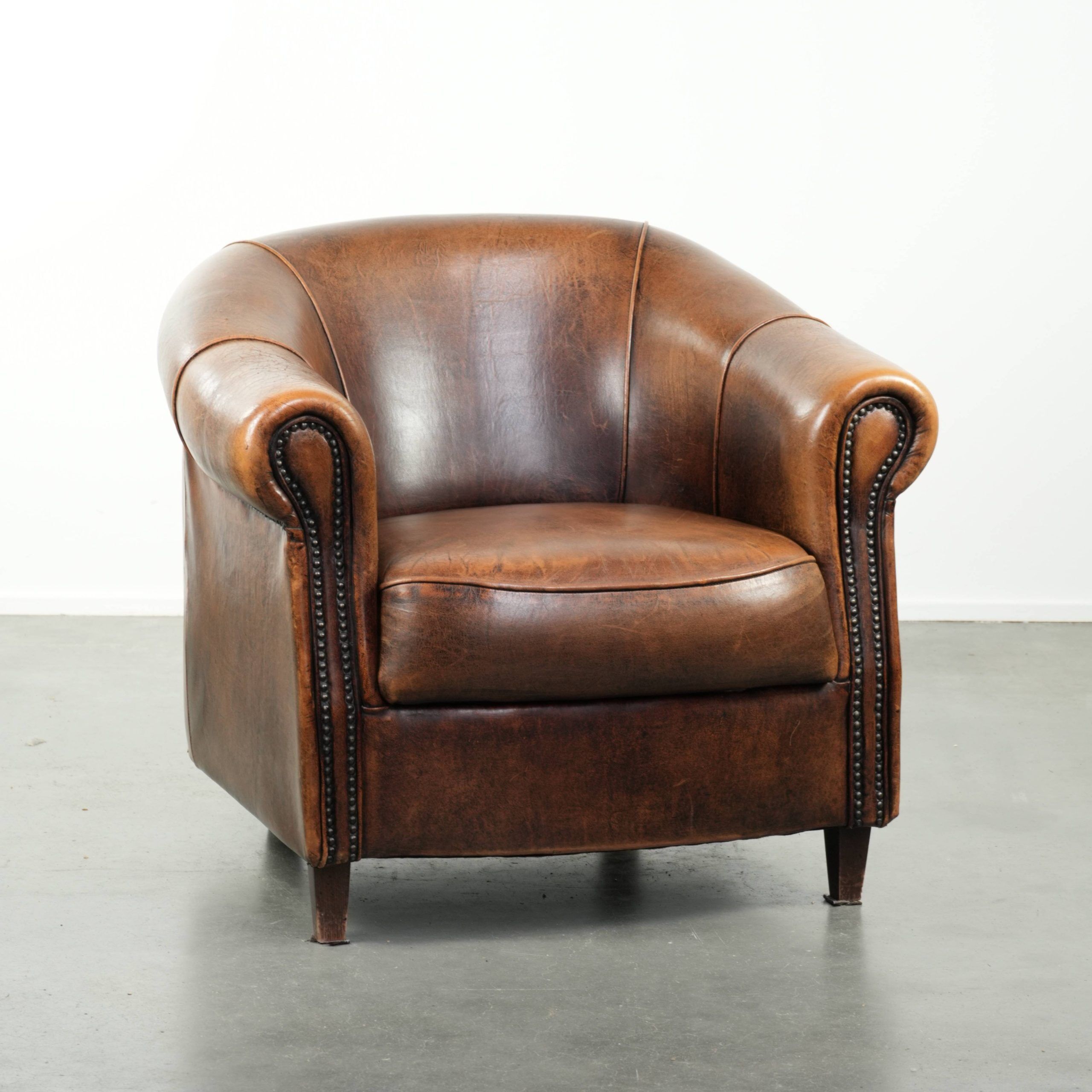 Fauteuil club en cuir de peau de mouton avec un coussin de siège fixe.