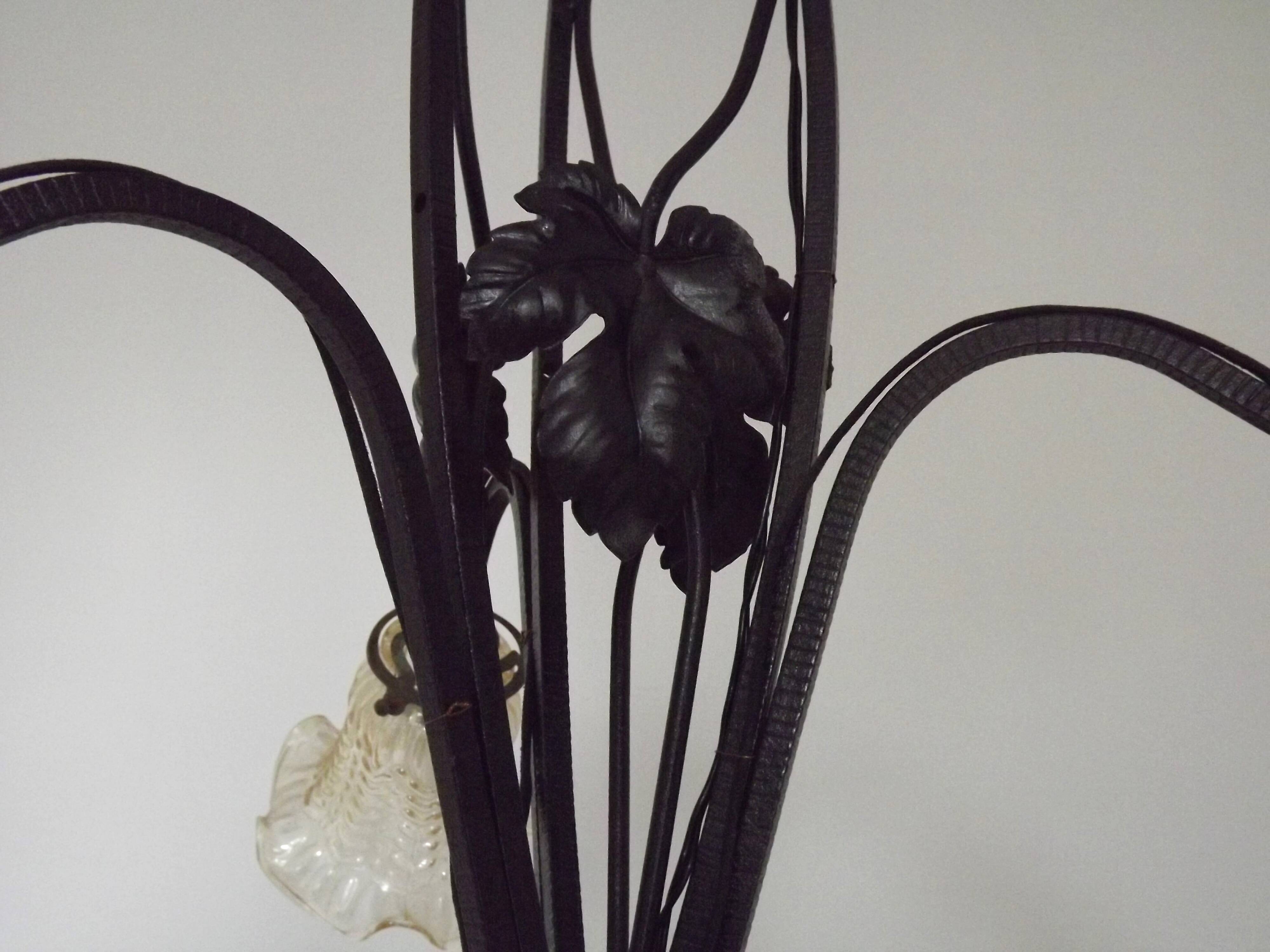 French Art Nouveau leaf detail iron three-light chandelier with amber glass shades.