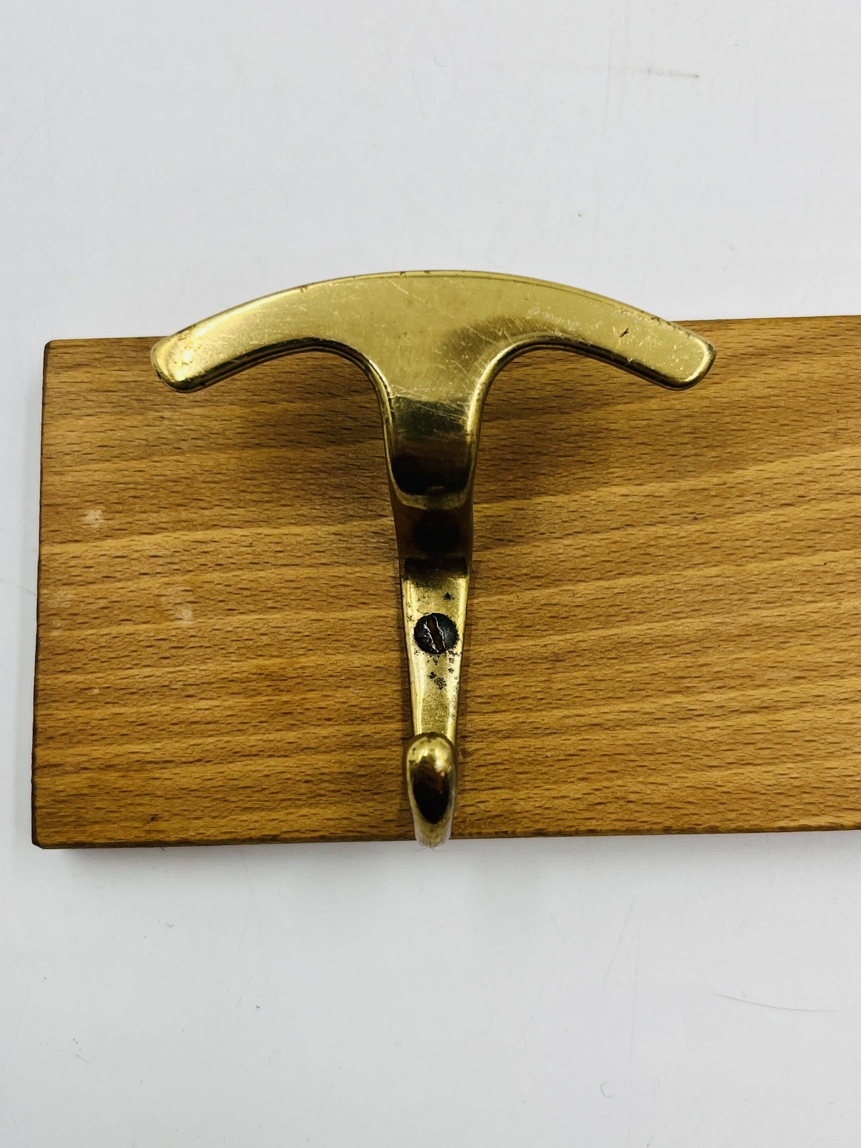 Vintage wall coat rack in brass and wood design.